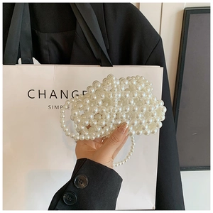 Close-up of handmade mini pearl woven cloud bag with elegant beaded chain strap
