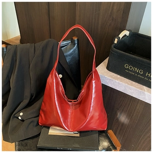 Detail of red glossy patent leather tote bag with wide shoulder strap in home setting