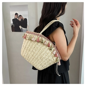 Detail of hand-woven straw tote bag with colorful tassels and a drawstring closure