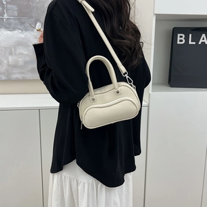 Detail of cream-colored lychee leather handbag with wavy zipper and silver studs