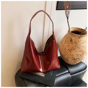 Detail of a deep red oil-wax leather hobo shoulder bag placed on a vintage background