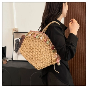 Detail of hand-woven straw tote bag featuring colorful tassels for summer beach vacation