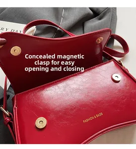 Détail du sac bandoulière rouge brillant avec fermoir magnétique et lettrage doré