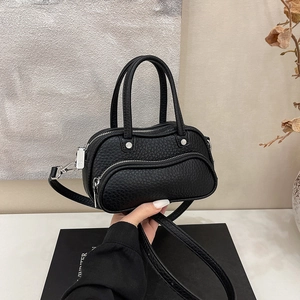 Detailed macro view of black pebble grain leather texture and silver zipper on the mini bag
