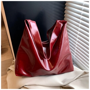 Close-up of deep wine red glossy tote bag showing high-shine leather texture and wide handle