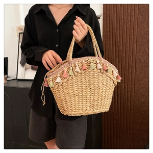 Close-up of handmade straw tote featuring colorful fringe tassels and woven texture