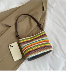 Détail du sac à main tissé rayé arc-en-ciel avec fines lanières brunes et nœuds décoratifs