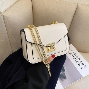 Borsa a tracolla vintage beige con catena dorata su un divano moderno e minimalista