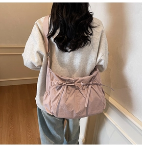 Detail of lavender nylon crossbody bag featuring cute bow ties and ruched design