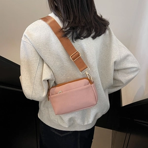 Pink crossbody bag with brown woven strap and gold hardware shown in a side view