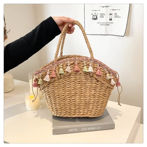 Detail of handmade straw bag featuring colorful tassels and brown drawstring closure