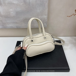 Detail of off-white lychee grain leather handbag with silver hardware and wavy zipper pocket
