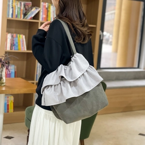 Sac seau chic en toile grise avec rabat à volants violets dans une bibliothèque sobre