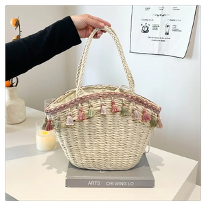 Detail of bohemian straw tote bag with multi-colored fringe and woven texture