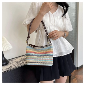 Détail du sac seau en paille colorée avec bandoulière en cuir marron et nœuds décoratifs