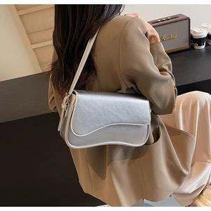 Détail du sac sous le bras argenté métallisé avec texture brillante et rabat ondulé