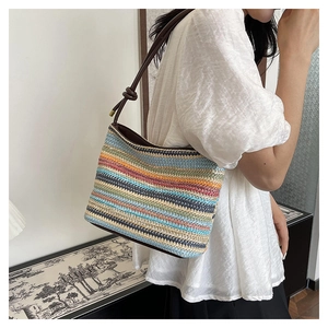 Détail du sac à bandoulière tressé à rayures colorées et anse en cuir marron foncé