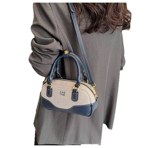 Chic canvas and navy leather bowling bag with top handles and adjustable strap