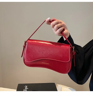 Détail du sac d'épaule en cuir brillant rouge avec fond ondulé et lettrage doré