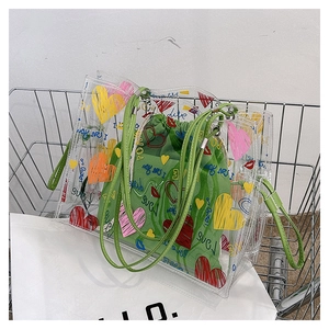 Close-up of transparent PVC tote bag with green drawstring pouch and heart love patterns