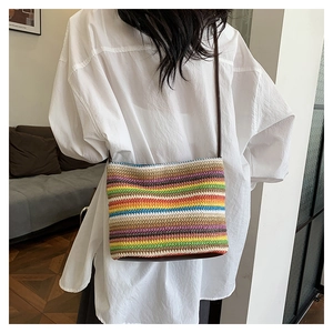 Détail du sac bandoulière tissé à rayures arc-en-ciel sur une chemise blanche