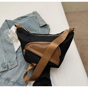 Black nylon shoulder bag featuring brown leather pocket detail and gold hardware zippers