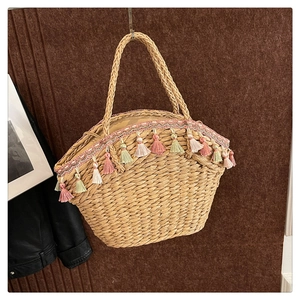 Detail of straw handbag featuring colorful tassels and intricate lace embroidery trim