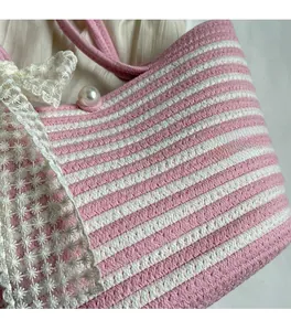 Detail of pink and white woven straw bag featuring delicate lace trim and a pearl accent