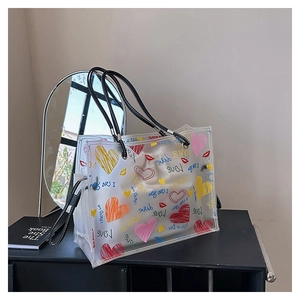 Close-up of clear PVC tote with colorful heart prints and black leather handles