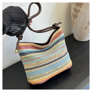 Détail du sac seau en paille tissée colorée avec rayures et bandoulière à nœuds