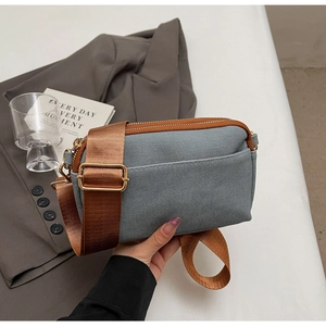 Gray-blue square crossbody bag with dual zippers and adjustable wide fabric strap