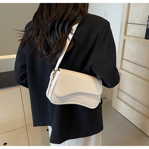 Détail du sac à bandoulière crème avec rabat asymétrique et lettrage doré chic
