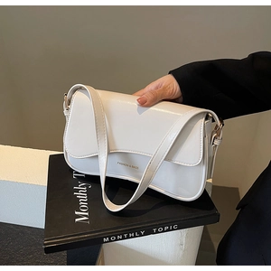 Détail d'un sac sous le bras blanc crème en cuir PU brillant avec ferrures dorées