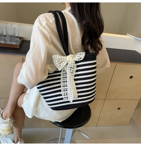 Detail view of large striped woven beach bag with delicate lace floral bow and rope handle