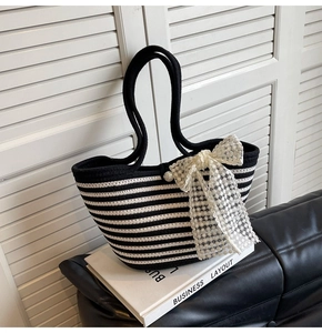 Detail view of woven striped tote bag with elegant white lace bow and pearl buckle