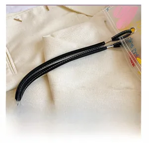 Close-up of black leather handles with white stitching and gold metal buckles