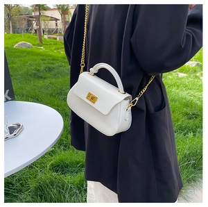 Close-up of white crossbody bag with gold chain strap on a black blazer outfit