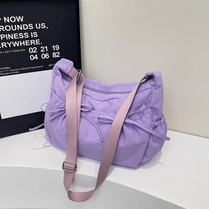 Lavender purple nylon crossbody bag with cute bows on a modern white display stand