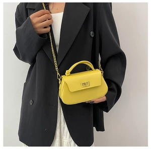 Detail of yellow mini flap bag with gold chain strap on black blazer outfit