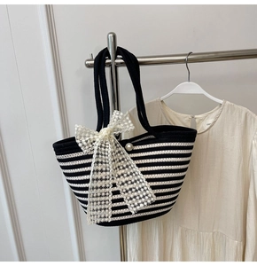 Close-up of striped woven tote with a large lace bow and elegant pearl embellishment