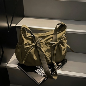 Olive green canvas crossbody bag with drawstring bow details and wide shoulder strap