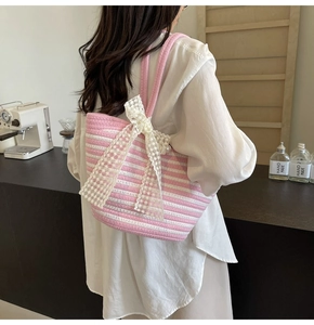 Detail of pink striped woven tote bag featuring a decorative white lace bow accent