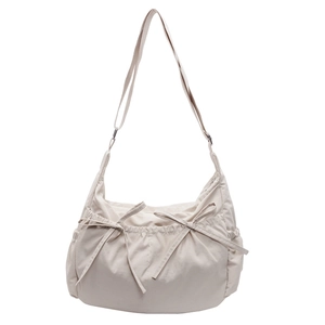 Minimalist beige canvas crossbody bag with decorative bows and adjustable strap