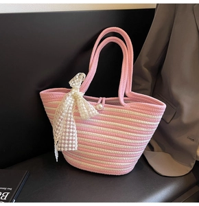 Detail of pink striped woven tote bag featuring a lace bow and pearl closure decoration