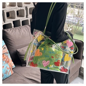 Detail of transparent PVC tote bag with green drawstring pouch and colorful love prints
