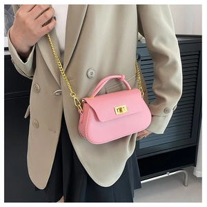 Pink crossbody bag with gold chain strap and turn-lock shown with a minimalist blazer outfit