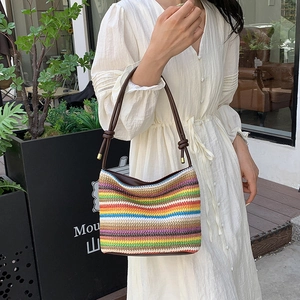 Sac seau en paille rayé arc-en-ciel avec bandoulière cuir sur robe blanche