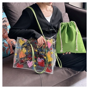 Detail view of transparent PVC tote bag with graffiti hearts and green canvas inner pouch