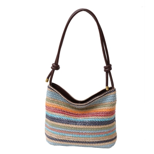 Sac seau en paille tissé à rayures colorées avec des anses en cuir marron sur fond blanc