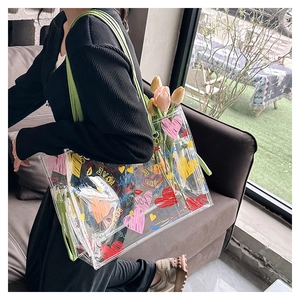 Detailed shot of transparent PVC tote bag with colorful heart prints and green straps